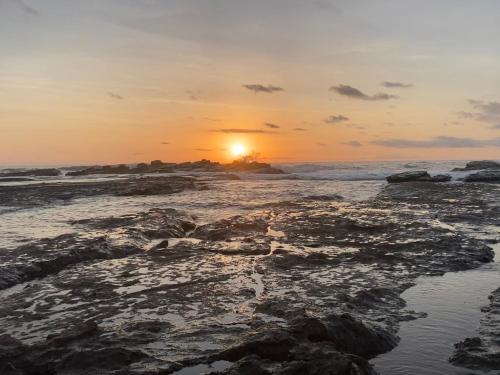 a sunset on the beach with rocks at Pacific View Condominium in Playa Azul in Playa Azul