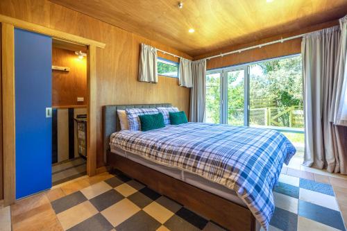 a bedroom with a bed and a large window at Oneroa Beach Hideaway in Blackpool