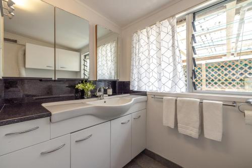 a white bathroom with a sink and a window at Oneroa Beach Hideaway in Blackpool