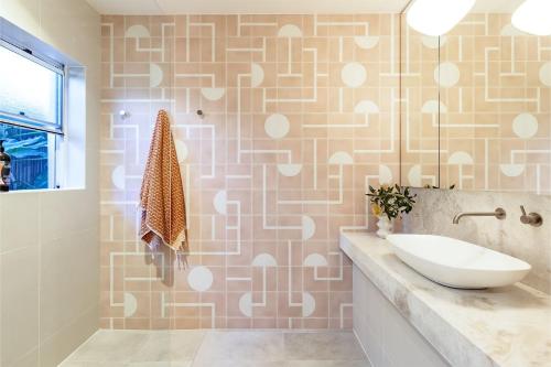 a bathroom with a sink and a tile wall at Celeste, 26 Bonito Street - Tranquil, Stylish & Pet friendly in Corlette