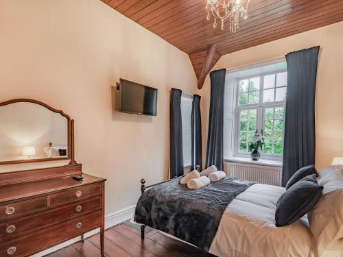 a bedroom with a bed and a mirror and a dresser at Groudd Hall in Cerrigydrudion