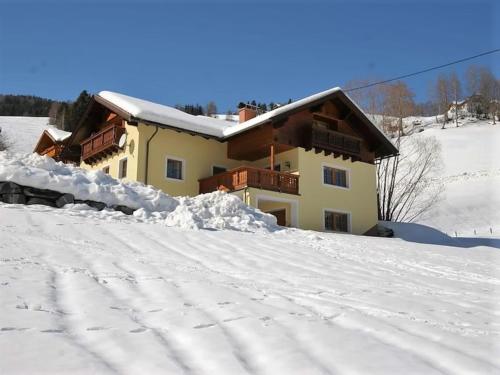 a house on a snow covered hill with a building at Wirnsberg in Aschbach