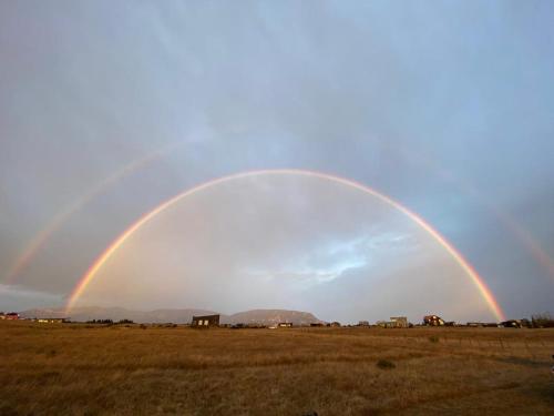 a double rainbow in the sky over a field at Casa Aoni in Puerto Natales