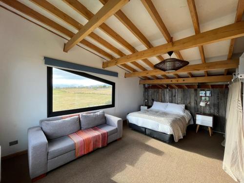 a bedroom with a bed and a couch and a window at Casa Aoni in Puerto Natales