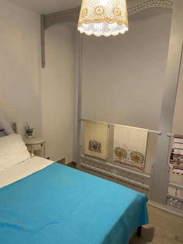 a bedroom with a blue bed and a chandelier at Mpasales house in Skiros