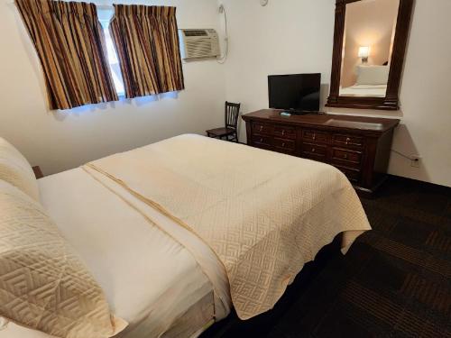 a bedroom with a bed and a dresser and a mirror at Silver Saddle Motel in Manitou Springs