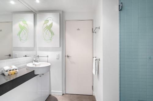 a white bathroom with a sink and a shower at 703 Harbour Lights Cairns Apartment with water views in Cairns