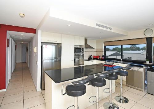 a kitchen with black counter tops and bar stools at Luxurious Beachfront Apartment in Hervey Bay