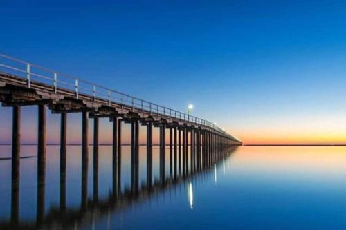 a long pier in the water with the sky at Luxurious Beachfront Apartment in Hervey Bay