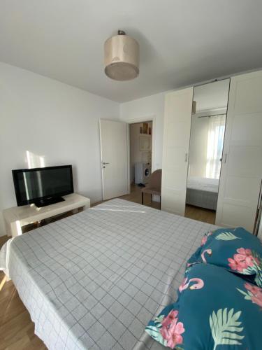 a bedroom with a bed and a flat screen tv at New building with private parking, big balcony and a stunning view in Bragadiru