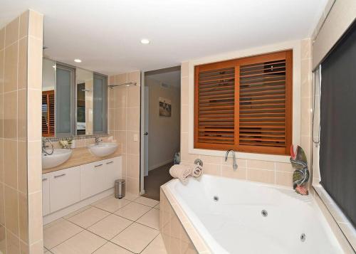 ein großes Bad mit einer Badewanne und 2 Waschbecken in der Unterkunft Luxurious Beachfront Apartment in Hervey Bay