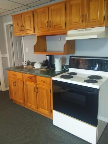 a kitchen with a black and white stove and wooden cabinets at Peaceful restful & fun on the water in Golden Lake