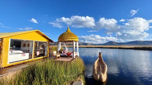 ein gelbes Haus mit einem Pavillon auf einem Fluss in der Unterkunft Uros Lodge Perú in Puno