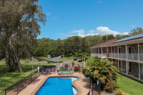 an aerial view of a swimming pool in front of a building at Aston Motel Yamba in Yamba
