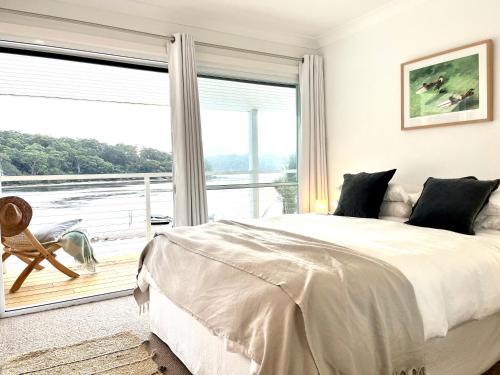 a bedroom with a bed and a large window at The Sandbar House, Royal National Park, waterfront beach house in Maianbar