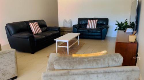 a living room with two couches and a table at Downtown Narrabri Apartment in Narrabri