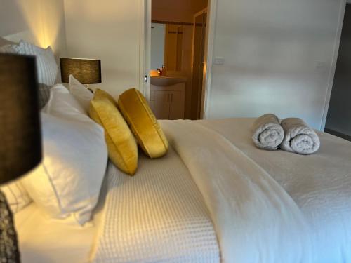 a white bed with pillows and towels on it at Downtown Narrabri Apartment in Narrabri