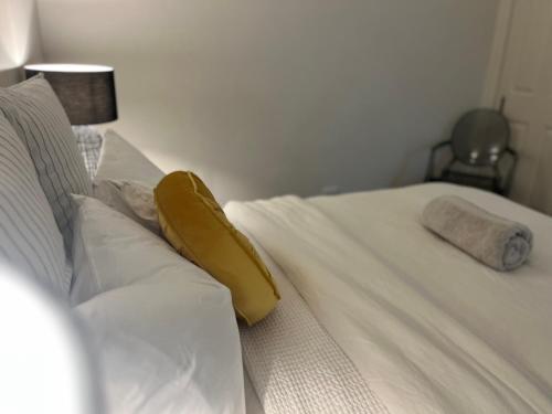 a white bed with a yellow pillow on it at Downtown Narrabri Apartment in Narrabri