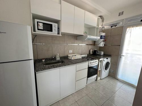 a small kitchen with white cabinets and a microwave at DON SIMON Apart 8 -departamento nuevo in Esperanza