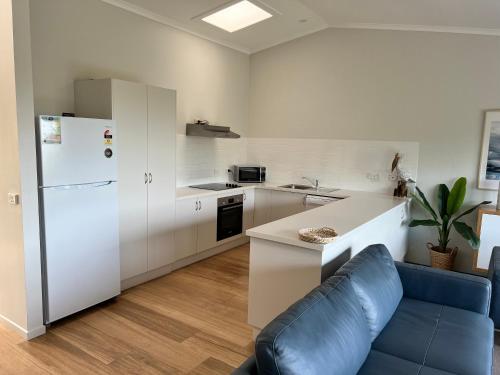 a kitchen with a white refrigerator and a blue couch at BlueWater Apartments in Merimbula