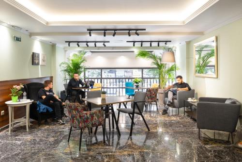 un groupe de personnes assises à des tables dans un hall dans l'établissement Hotel El Greco, à Thessalonique