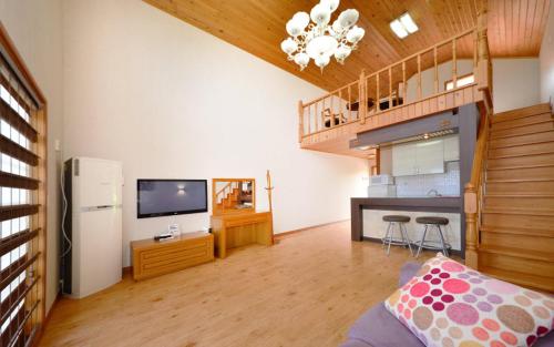 a living room with a television and a kitchen at Amigas Ocean View Pension in Yangyang
