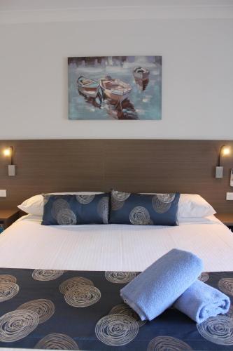 a bedroom with a large bed with blue pillows at Aston Motel Yamba in Yamba