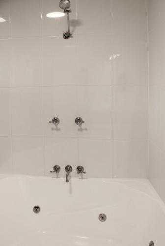 a shower with silver faucets in a bathroom at Aston Motel Yamba in Yamba