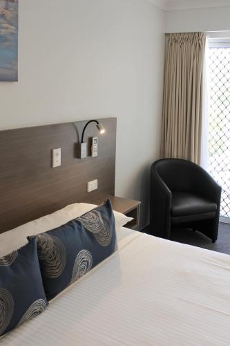 a hotel room with a bed and a black chair at Aston Motel Yamba in Yamba
