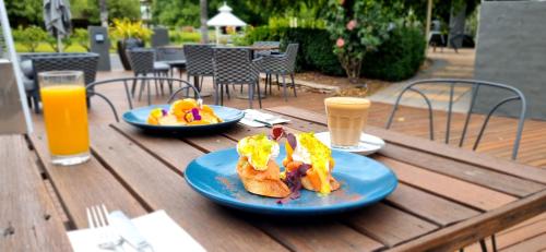 a table with two plates of food and two glasses of orange juice at Parklands Resort Mudgee in Mudgee