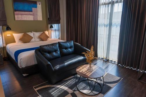 a hotel room with a bed and a couch and a table at Wealth Boutique Hotel Chiang Mai in Chiang Mai
