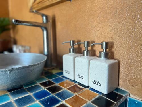 two soap dispensers sitting on a counter next to a sink at NGÀI Villa in Phu Yen