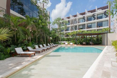 an outdoor pool with lounge chairs and a building at Chaac in Tulum