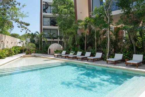 a swimming pool with lounge chairs and a building at Chaac in Tulum