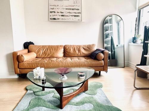 a living room with a couch and a glass table at Sunny & Cozy Apt with a Piano in a hot Brooklyn Neighborhood in Brooklyn