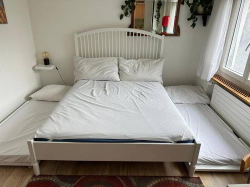 Una cama con sábanas blancas y almohadas en un dormitorio en Pipin’s Studio, en Ostermundigen