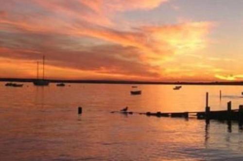 a person in a boat on the water at sunset at Cozy, cute beach condo in Westerly RI . Best value in Westerly!! in Westerly