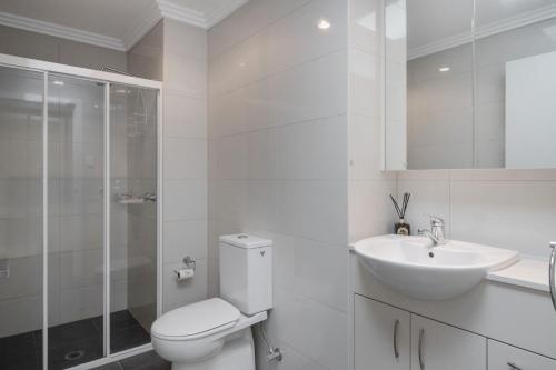a white bathroom with a toilet and a sink at Swan Lake Retreat in Berrara