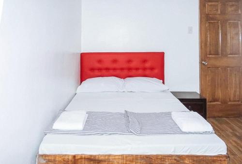 a bed with a red headboard in a room at Magabelle Guesthouse in Cebu City
