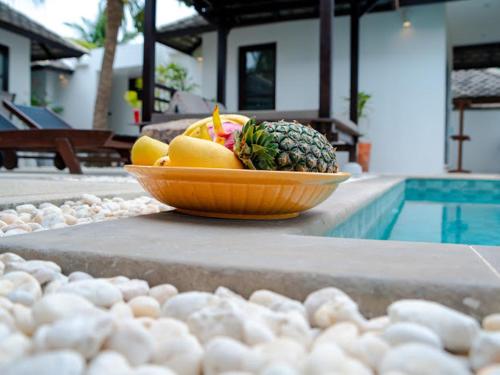 a bowl of fruit sitting next to a swimming pool at 3 Bedroom Seaview Villa Haven on Beachfront Resort in Koh Samui 