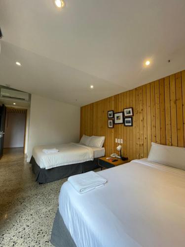 a hotel room with two beds and wooden walls at G1 Lodge in Baguio
