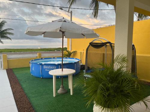 einen Tisch mit einem Sonnenschirm neben einem Whirlpool in der Unterkunft Casa Amarela Paripueira in Paripueira