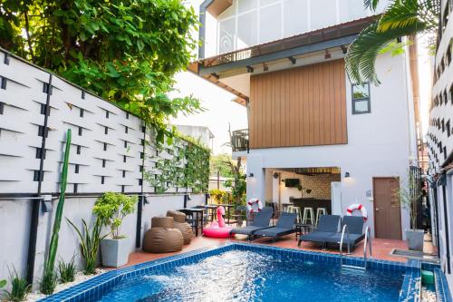 an outdoor swimming pool with chairs and a house at Wealth Boutique Hotel Chiang Mai in Chiang Mai