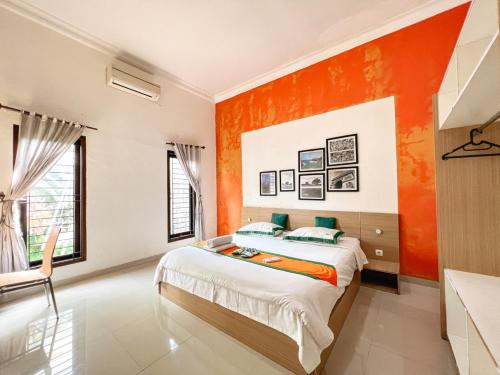 a bedroom with an orange accent wall and a bed at Homestay Sawitsari Dekat Pakuwon Mall dan UGM by Simply Homy in Yogyakarta