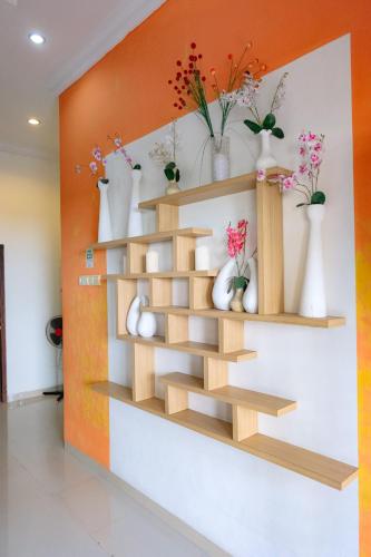 a shelf with vases and vases on a wall at Homestay Sawitsari Dekat Pakuwon Mall dan UGM by Simply Homy in Yogyakarta