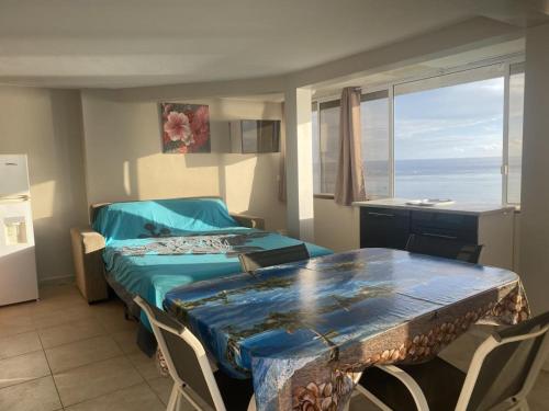 a bedroom with a bed and a table and chairs at chez Karine et Robert in Punaauia