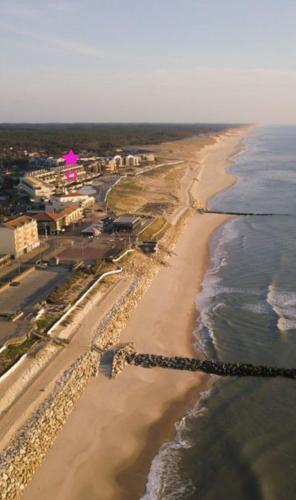 an aerial view of a beach with a pink building at L'Océan&Dunes vue à 180° en bord de plage in Lacanau-Océan