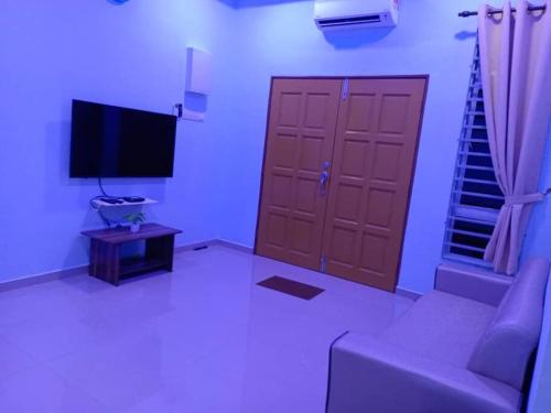 a living room with a couch and a television at Homestay Restu Mak Abah Private Pool Melaka in Merlimau
