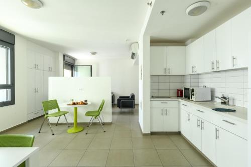 cocina con armarios blancos, mesa y sillas en דירות גני תערוכה - TLV university apartments near Expo by Sea N' Rent en Tel Aviv