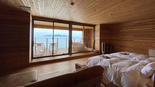 a bedroom with a bed and a view of the ocean at Genkai Ryokan in Munakata